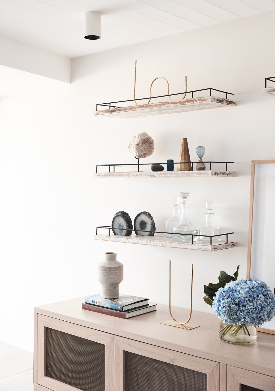 Floor-to-ceiling white-oak shelving and sideboard joinery styled with books and ceramics.