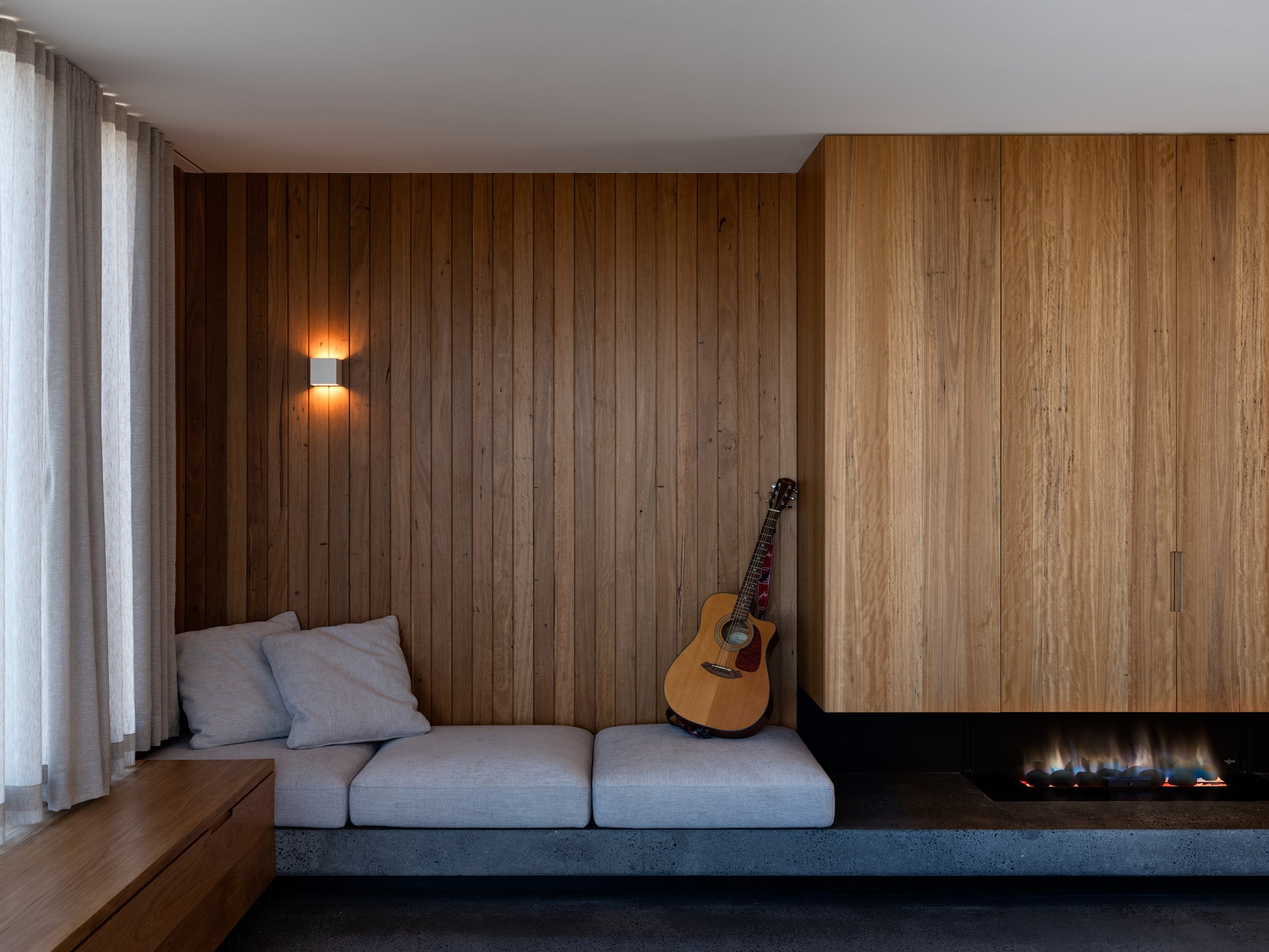 Timber-lined living room with a built-in bench seat and integrated fireplace surround.